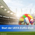 Stadionkurve mit vollbesetzten Rängen; mittig ein Fußball mit den Flaggen aller teilnehmenden Länder als Lederfelder