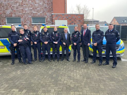 Polizisten und Innenminister vor Streifenwagen